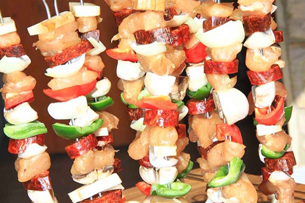 Friss zöldséges és húsos saslik nyársak, kerti mobil kemencében történő sütésre előkészítve